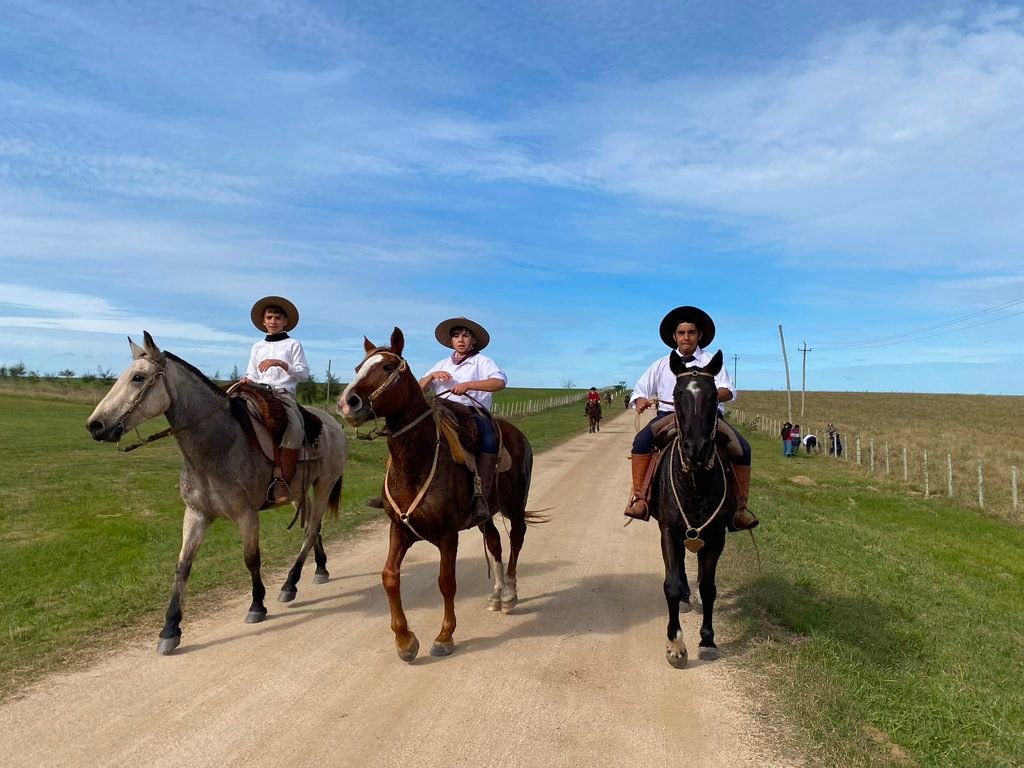 Tres estudiantes integrantes de la aparcería de la institución llegando a caballo luego de un desfile criollo
